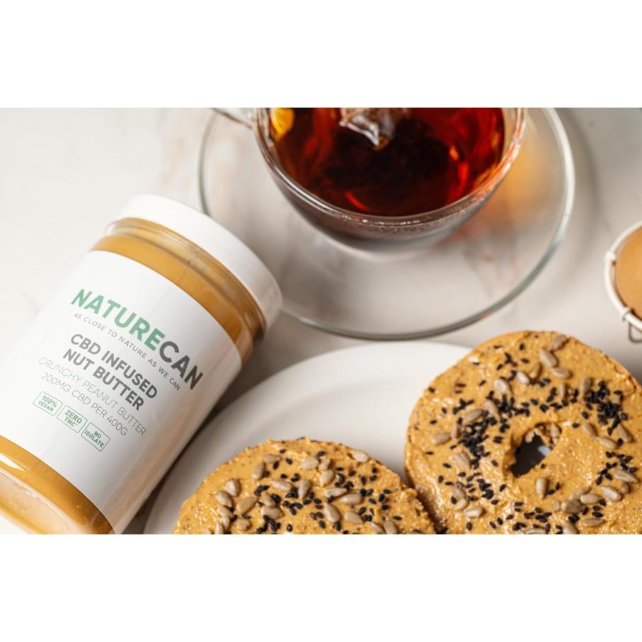 CBD nut butter shown on a bagel, next to the tub